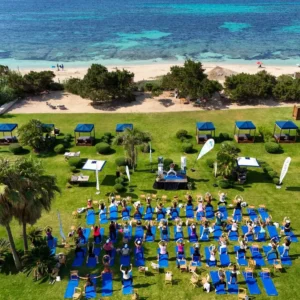 An outdoor yoga session during an edition of Formentera Zen, on the grass with the Mediterranean in the background. / Formentera Zen