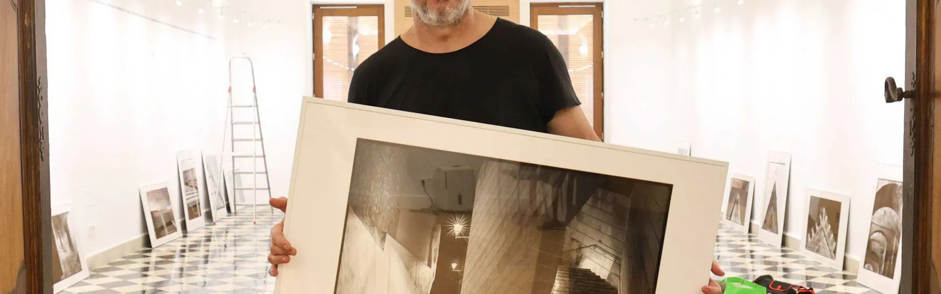 Joan Costa with one of his photographs while setting up the exhibition in the Refectori. / J.A. Riera
